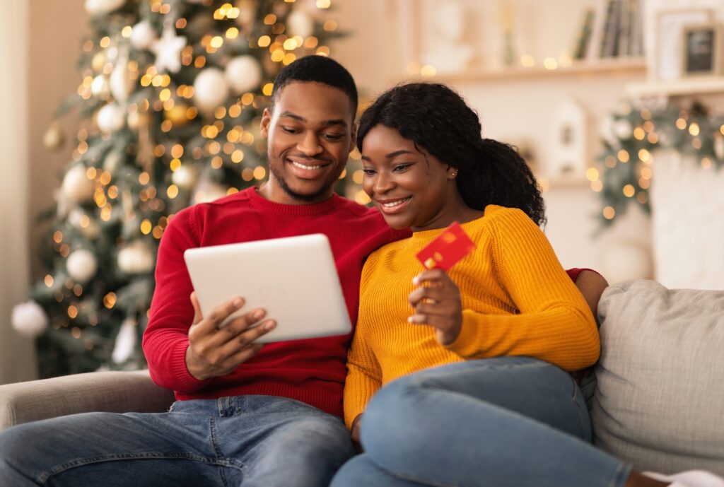 Couple reviewing online purchases on a tablet while holding a credit card during the holiday season