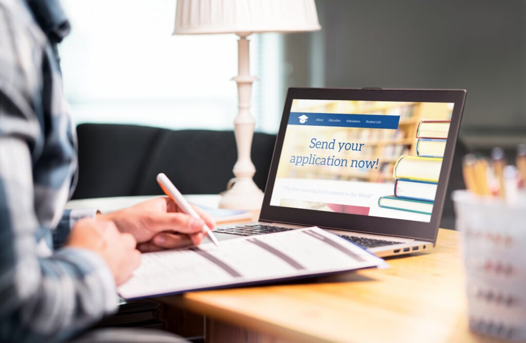 Do You Have to Pay Back Grants? Grants vs. Loans A person fills out a paper application beside a laptop displaying a college admissions website.