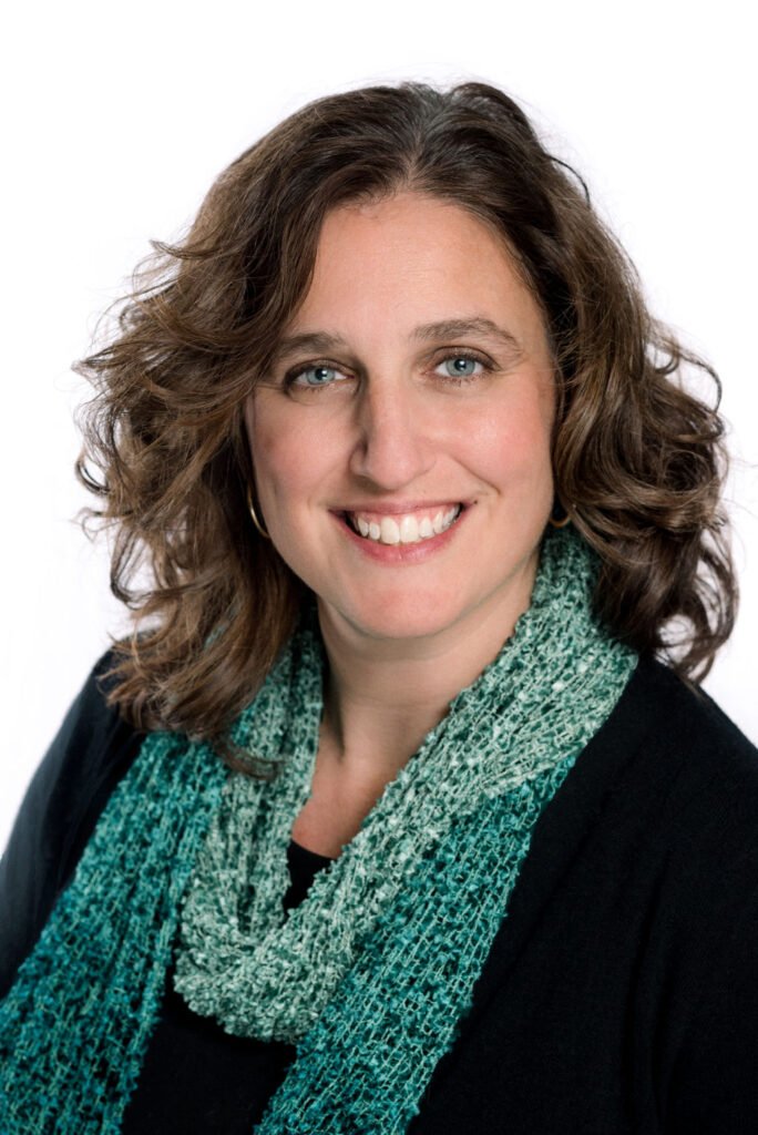 How Courtney Found Credit Card Debt Relief Smiling woman with shoulder-length brown hair wearing a green scarf against a white background.